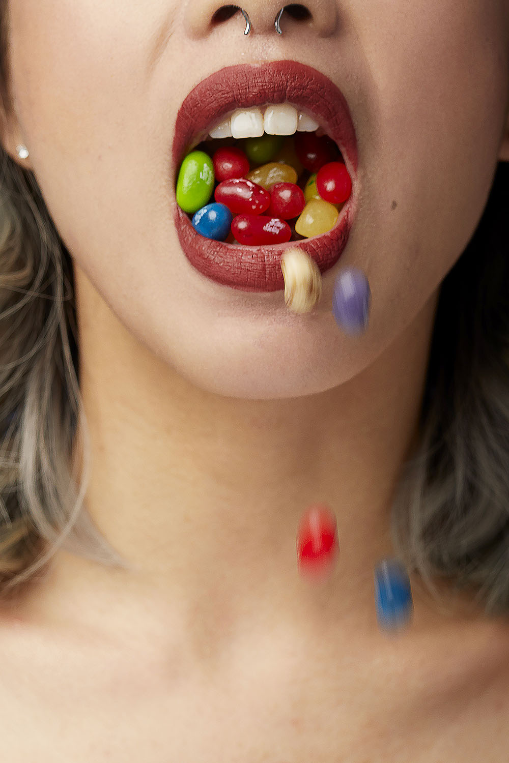 girl with red lipstick and jelly bean candy spilling out of her mouth